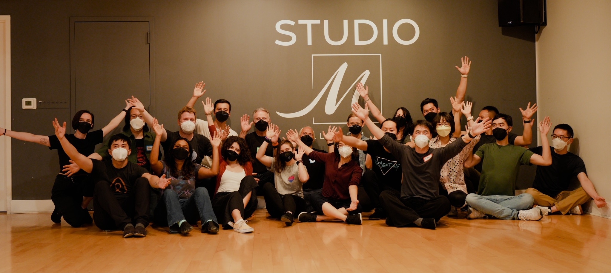 Students and staff of Do Your Own Swing posing merrily in front of a wall displaying Studio M